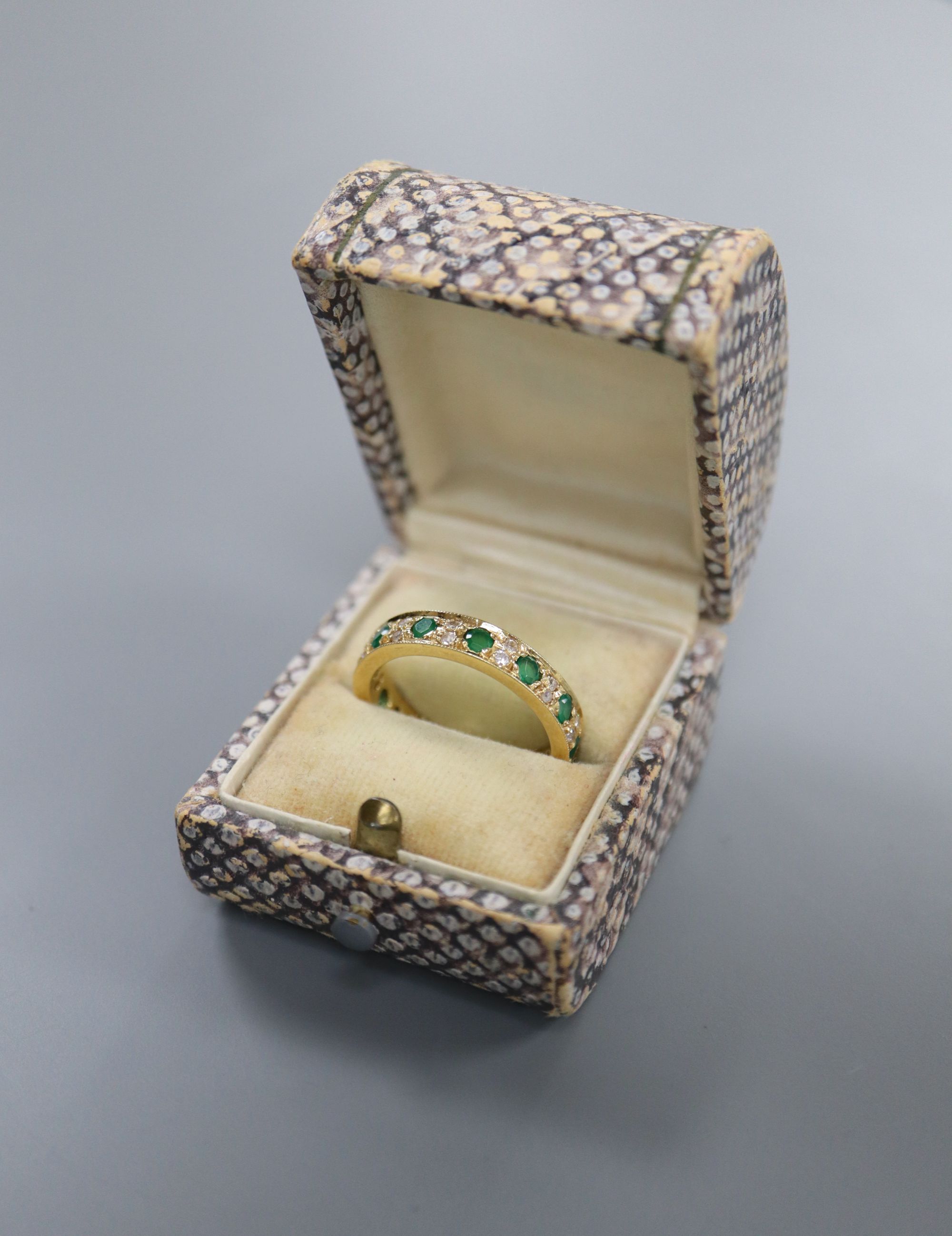 A mid to late 20th century yellow metal, emerald and diamond set full eternity ring, size P/Q, gross 5.7 grams.